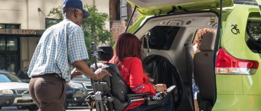 Woman seated in a wheelchair enters taxi