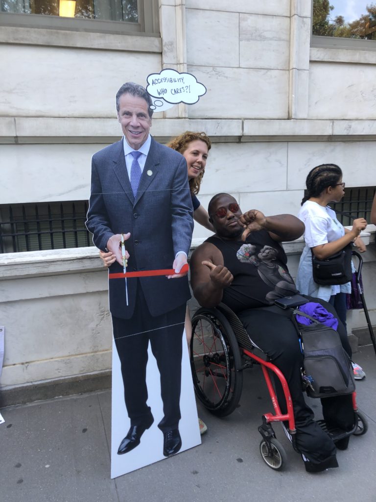 Image of 2019 Disability Pride NYC Parade participants posing with a comical cutout image of Governor Cuomo.