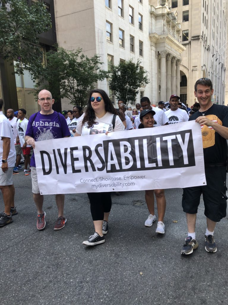 Four 2019 Disability Pride NYC parade goers holding a Diversability banner.