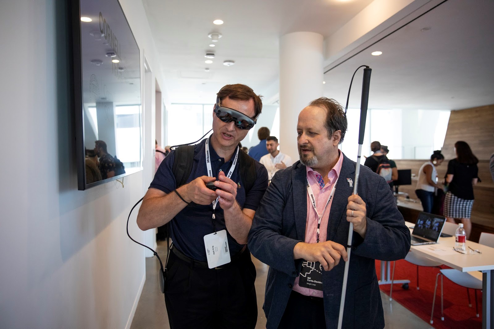 Bill Curtis-Davidson (former Accessibility Leader at Magic Leap) holds a white cane while giving a demo of the Magic Leap 1 spatial computing device to Matt King of Facebook during the 2019 XR Access Symposium in New York, July 2019.