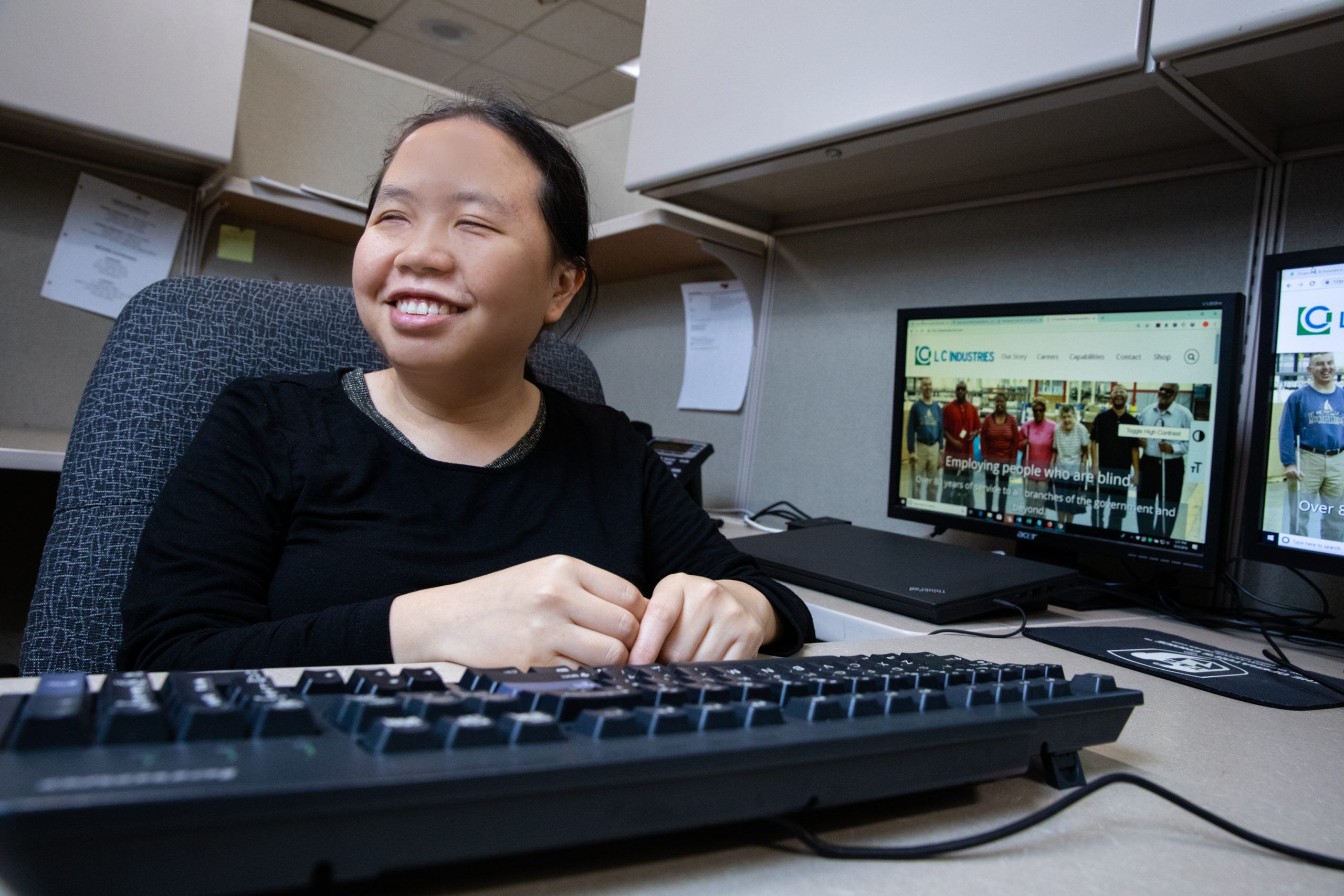 Blind professional tester Vanh Vue seated at her computer desk at LCI Tech.