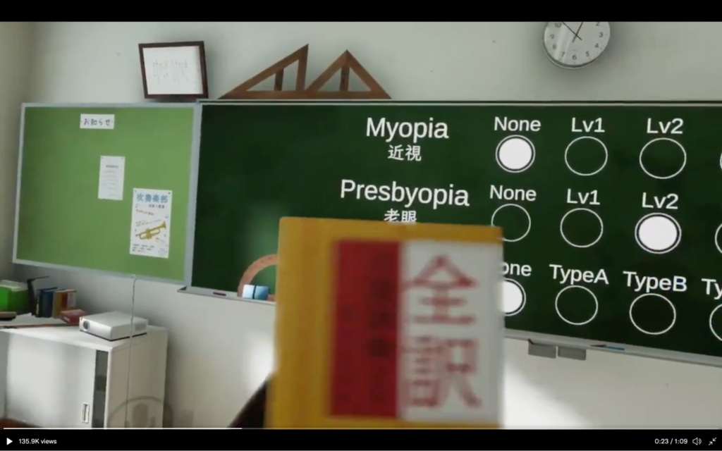 Screenshot of classroom with a book that's close and blurry while the blackboard is further away and clear to demo Presbyopia