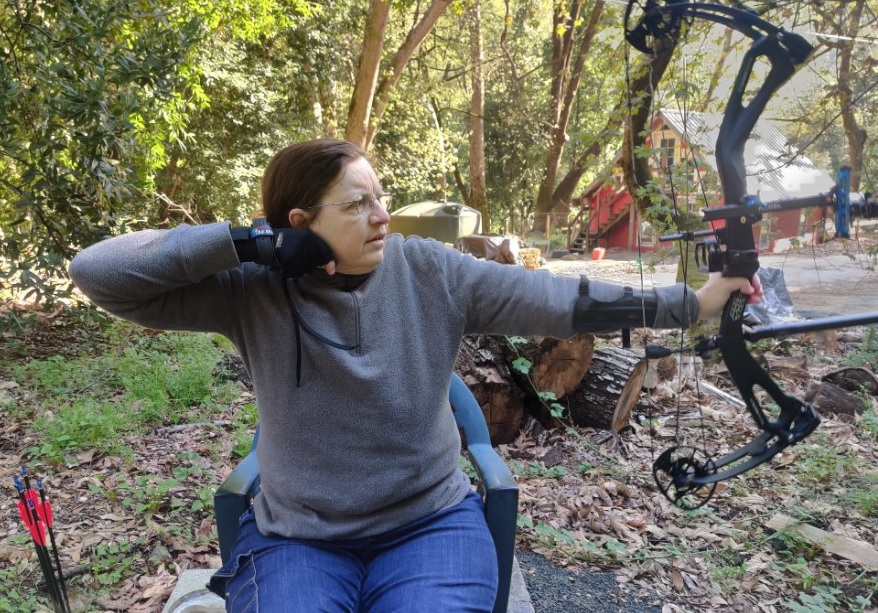 A seated Sheri Byrne-Haber holds an archery bow after shooting the arrow