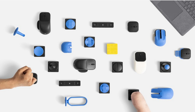Overhead view of a variety of Microsoft's accessible accessories sitting on a white desk.