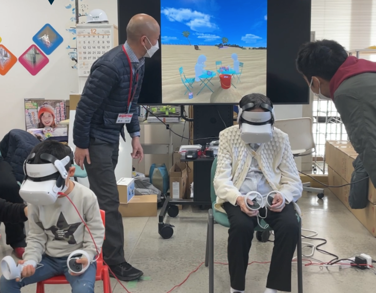 The child on the left engages in VR alone while the senior on the right has two staff members assisting with the controllers.