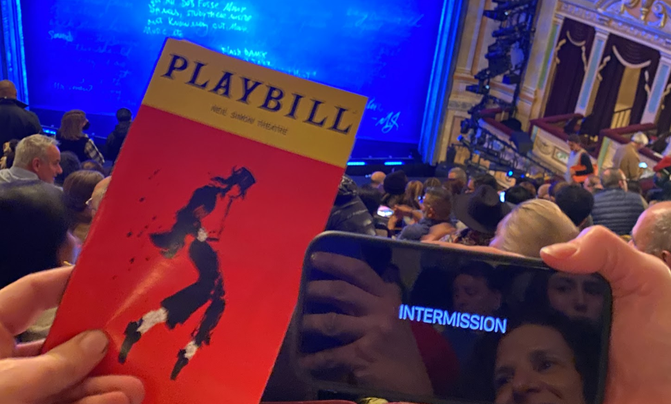 MJ: The Musical Playbill and iPhone screen showing "Intermission" overlooking the audience and stage.