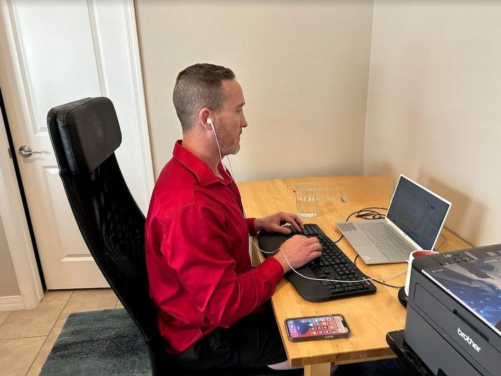 Tanner Gers sit at a desk typing on an external keyboard in front of the laptop