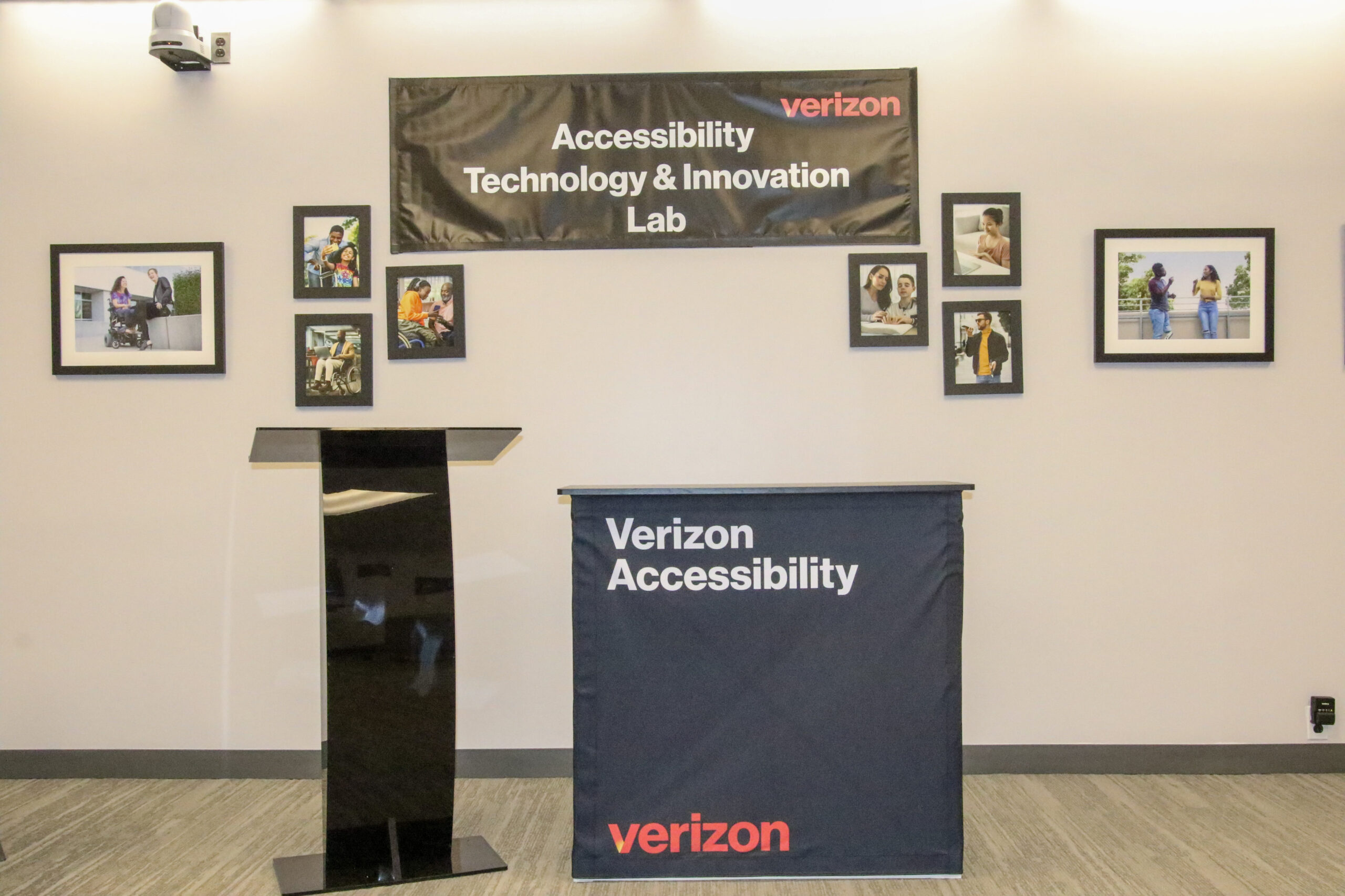 Collaboration space with a lectern and table. Behind the lectern are a banner and photos on the wall.