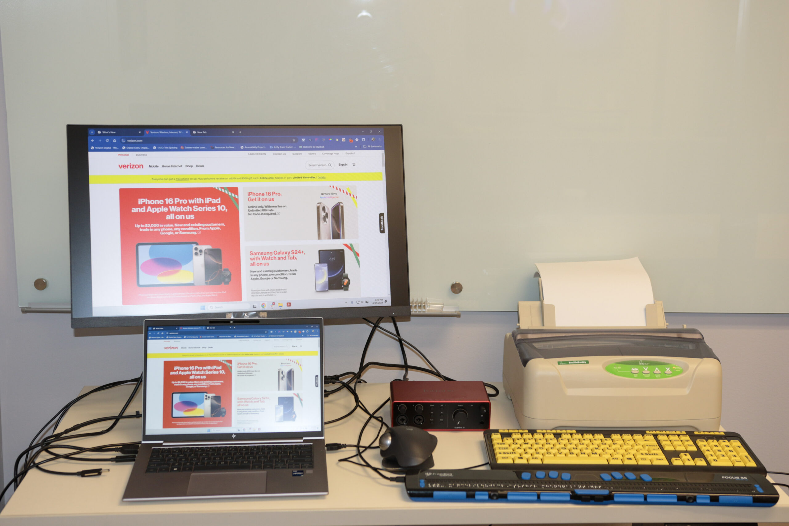 A table filled with Windows PC, Braille Display, High contrast keyboard, Braille Printer, PC with Jaws and NVDA Screen reader, Narrator, Dragon Naturally Speaking